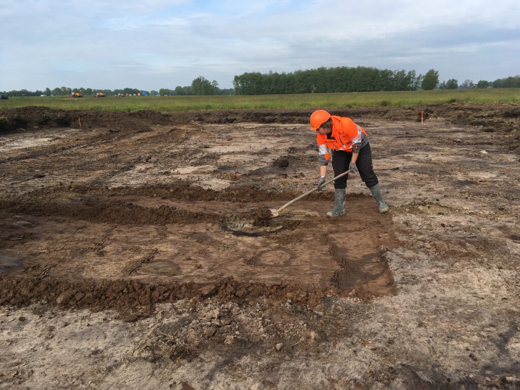 Archeoloog Roelien Rap schept de losse grond weg tijdens het couperen van de waterput. Het couperen werd met de graafmachine gedaan.